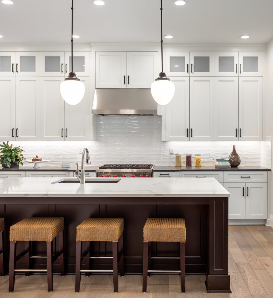 A modern kitchen with counter seating, marble countertops and custom lighting